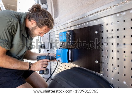 Man mounting electronic control units inside a camper van
