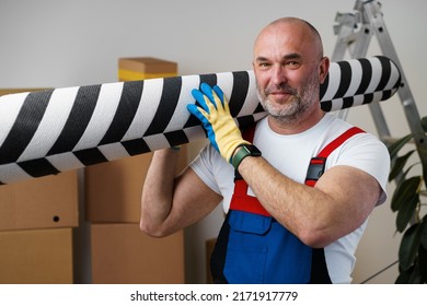 Man mover in uniform carrying big rolled carpet for relocation - Shutterstock ID 2171917779