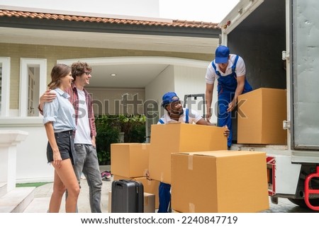 Man movers worker in blue uniform unloading cardboard boxes from truck.Professional delivery and moving service.