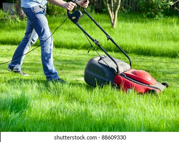 Man moves with lawnmower &  mows green grass