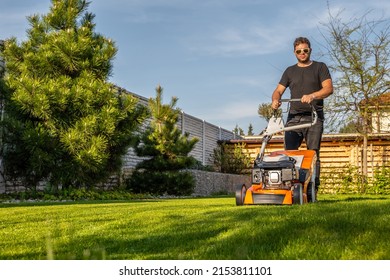 Man mowing lawn in the backyard of his house. Man with lawn mower. - Shutterstock ID 2153811101