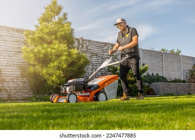 Man mowing lawn in the backyard of his house. Man with lawn mower.