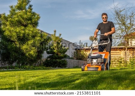 Man mowing lawn in the backyard of his house. Man with lawn mower. 商業照片 © 