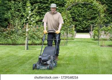 Man mowing a lawn in the grounds of a luxury home, lawncare and grass maintenance, UK