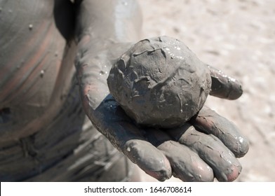 A Man In The Mud Sculpts A Ball