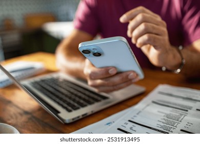 Man multitasking with laptop and phone on kitchen desk at home - Powered by Shutterstock