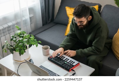 Man music producer or arranger using laptop and midi keyboard and other audio equipment to create music at home studio. Beat making and arranging audio content and composing song concept - Powered by Shutterstock