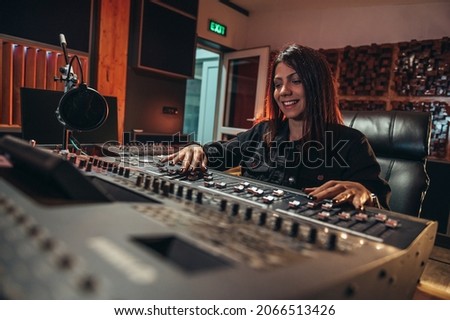 man music producer working on a mixing soundboard while in her studio