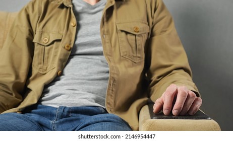 Man in mustard jacket sits in soft armchair tapping fingers on armrest against grey wall at home. Freelancer takes break after hard work closeup - Shutterstock ID 2146954447