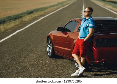 A Man Near The Red Sportscar On A  Background Steppes 