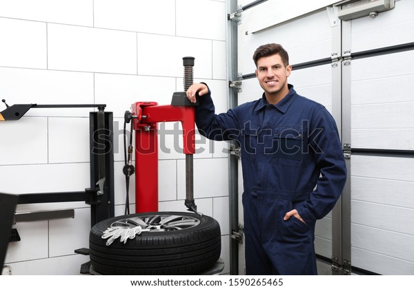 Man near tire\
fitting machine at car\
service