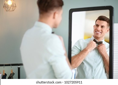 Man In New Outfit Looking At Himself In Mirror Indoors. Fashionable Wardrobe