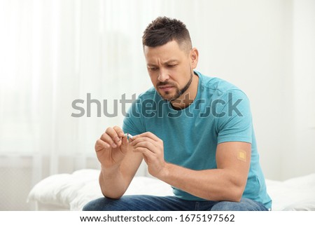 Man with nicotine patch and cigarette in bedroom