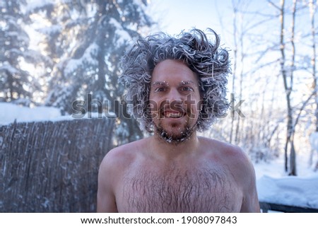 Man with no shirt on, chest showing in winter time with frozen, frosty hair from freezing cold winter day in northern Canada. 