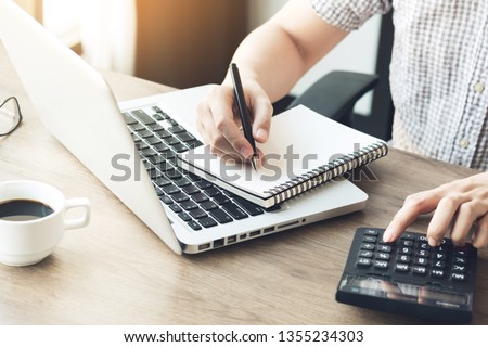 Man is note on notebook and using caculator to calculate the cost analysis. Business concept.