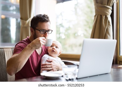 Man with notebook in cafe drinking coffee, holding his son