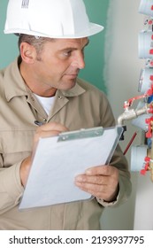 Man Noting Water Meter Reading On Clipboard