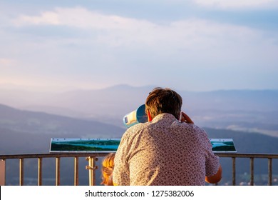 The man from the observation tower  in Coin-operated binoculars looks at the mountains. View from back. - Powered by Shutterstock