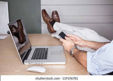 Man In Office With Feet On Desk And Laptop - Landscape Interior.