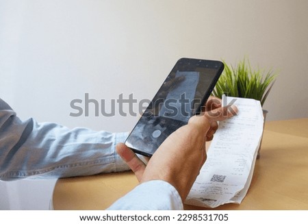man in an office taking a picture of a purchase ticket in order to upload it to his accounting software