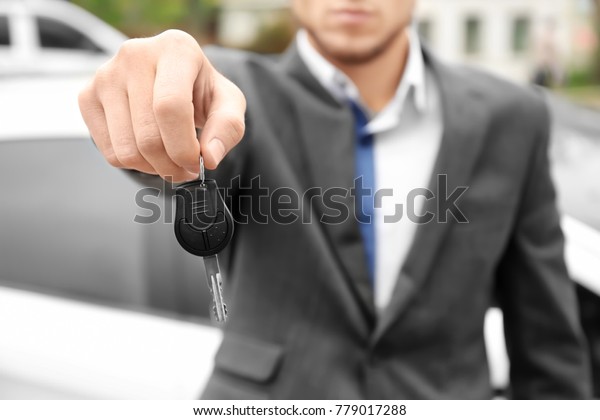Man in office\
wear holding car key\
outdoors