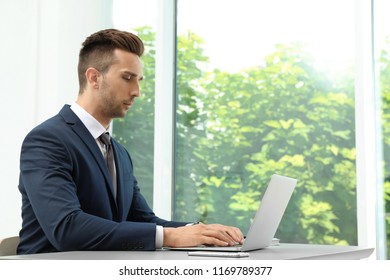 Man in office wear using laptop at table indoors - Shutterstock ID 1169789377