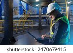 Man at oil refining factory. Fuel enterprise. Manager with laptop near manufactory. Man works in oil refining industry. Industrialist in reflective vest. Technologist servicing oil refining factory