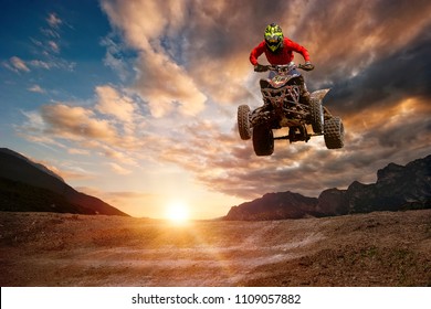 Man on atv jump on the trail during sunset.