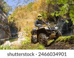 Man on ATV in mountains. Guy on quad bike. Off-road driving. Quad biker loves extreme sports. Male ATV driver near river. Extreme man looks away. Dangerous sports with ATV. Quad bike driver