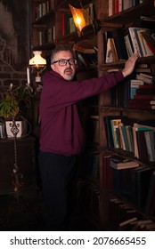 A man on the background of a bookcase with space for text or advertising. Brutal man with glasses 50 years old