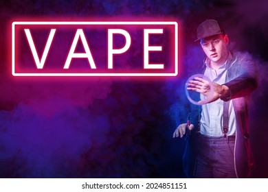 A man on the background of a bright inscription VAPE. Vaper on a dark background. A man shows a smoke ring from an electronic cigarette. A young man with a VAPE on a dark background.