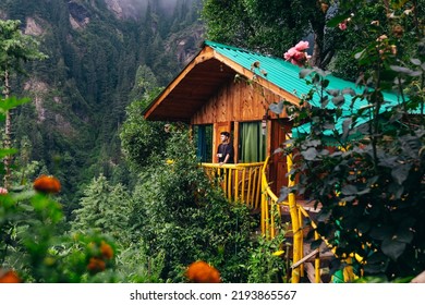 Man On Balcony Of Wooden Treehouse Hidden In The Cedar Forest Of Jibhi Mountains In North India