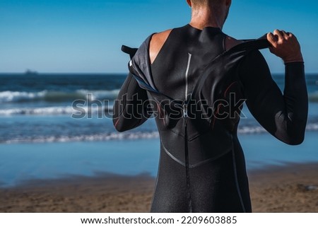 Man on the beach takes off his wet wetsuit after his surf lesson 商業照片 © 