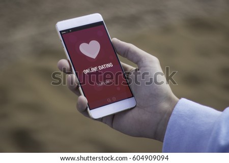 Man on the beach using online dating app with his mobile smart phone
