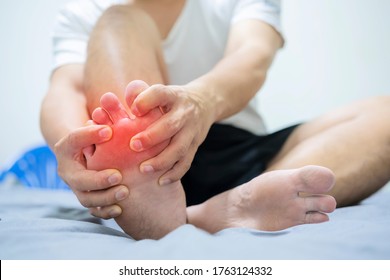Man on bed with pillow embrace foot with painful swollen gout inflammation - Shutterstock ID 1763124332