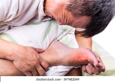Man on bed with pillow embrace foot with painful swollen gout inflammation