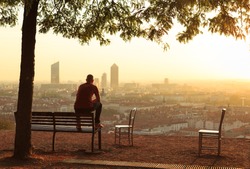 Man On A Bench Relaxing And Enjoying The Summer Sunrise Over A City. Lyon, France.