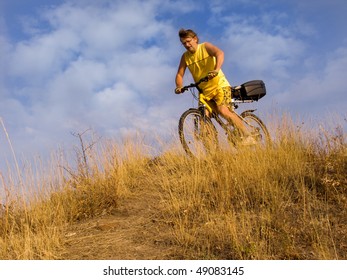 The man on a bicycle on a background of the cloudy sky