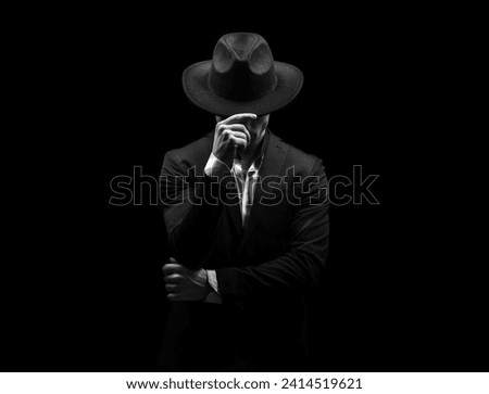 Man on a black background in a suit and hat