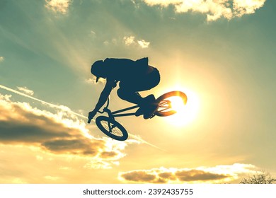 Man on bmx bike against sunshine sky. High BMX jump. Biker silhouette doing an jump. - Powered by Shutterstock