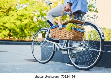 A man on a city bicycle holds picnic basket. - Shutterstock ID 731244544