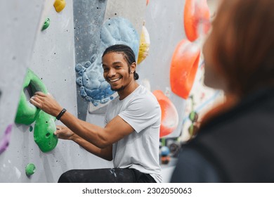 Man On Climbing Wall At Indoor Activity Centre Receiving Personal Lesson From Coach - Powered by Shutterstock