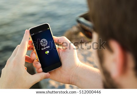 man on the coast checking roaming on his smartphone. All screen graphics are made up.