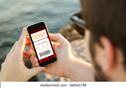 Man On The Coast Using His Smartphone To Buy Cinema Tickets. All Screen Graphics Are Made Up.