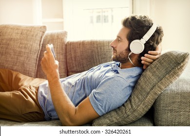 Man on couch watches a movie on mobile phone - Shutterstock ID 326420261
