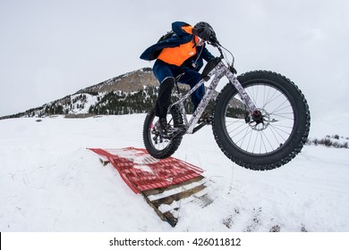 Man On Fat Bike Going Off Jump In Snow.