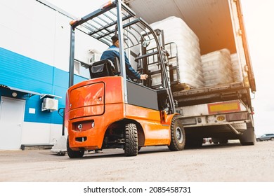 A man on a forklift works in a large warehouse, unloads bags of raw materials - Shutterstock ID 2085458731