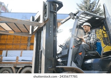 A man on a forklift works in a large warehouse, unloads bags of raw materials. - Powered by Shutterstock