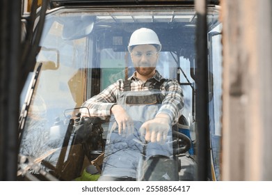 A man on a forklift works in a large warehouse, unloads bags of raw materials. - Powered by Shutterstock