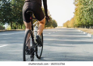 Man on a gravel bike on the road, back view. Legs of a cyclist riding a modern bicycle outdoors - Powered by Shutterstock